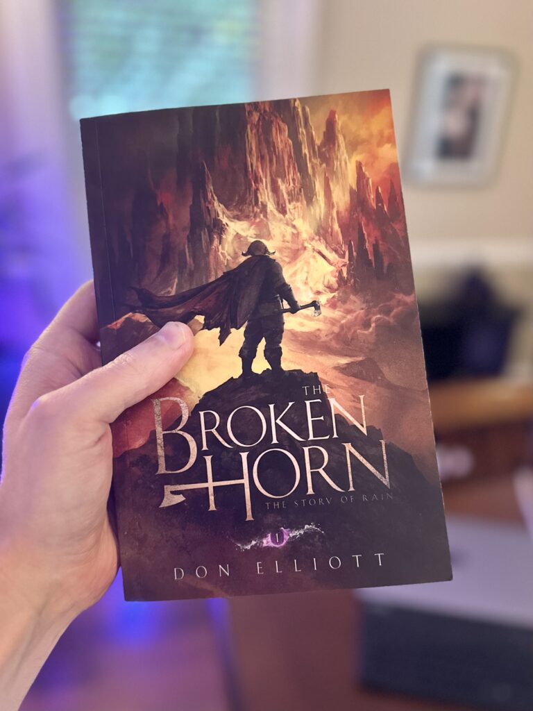 Don Elliott holding up a paperback copy of The Broken Horn